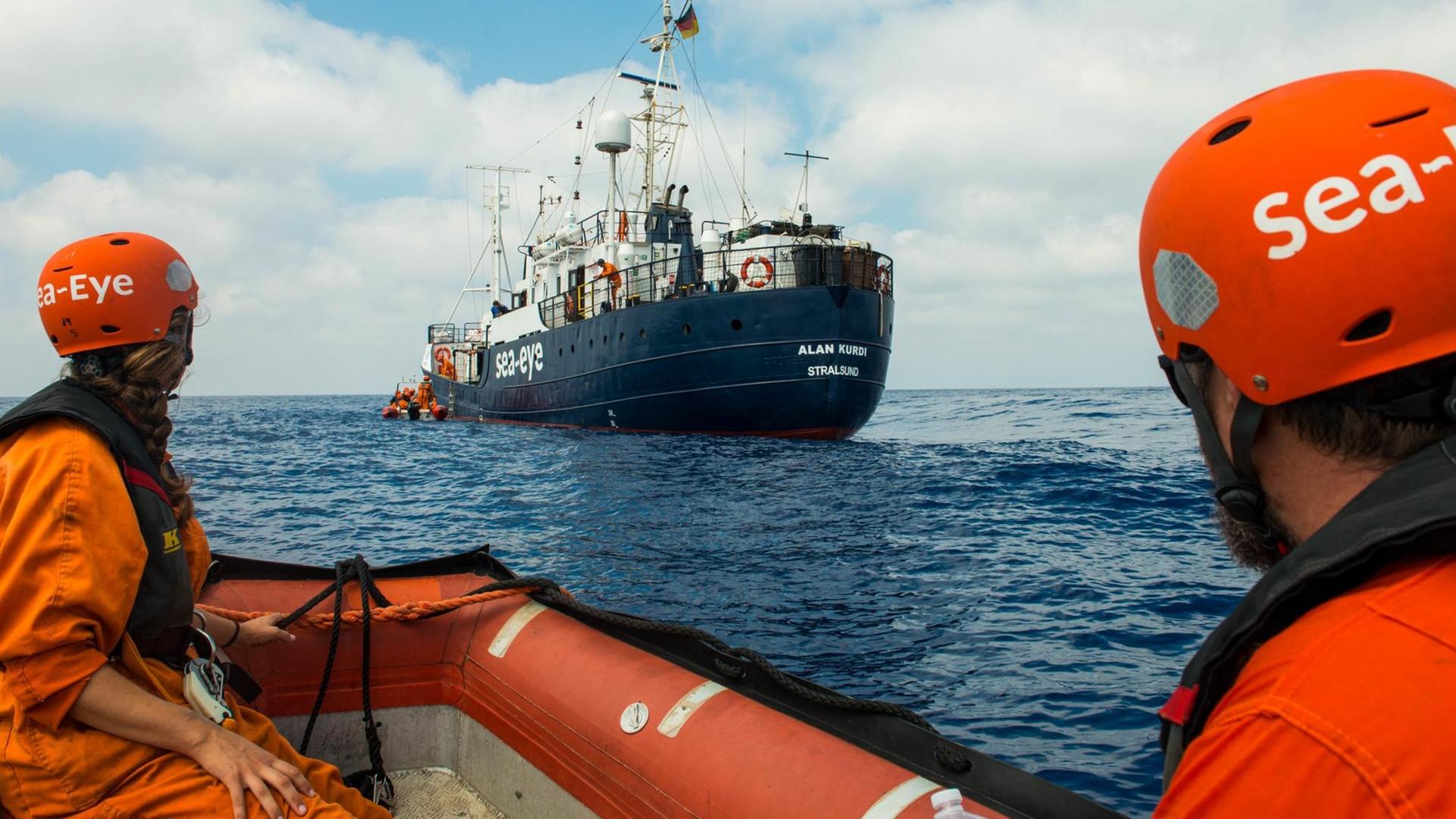 Die von der Seenotrettungsorganisation Sea Eye herausgegebene Aufnahme zeigt zwei Seenotretter in einem Schlauchboot, die zum Rettungsschiff «Alan Kurdi» hinüberschauen.