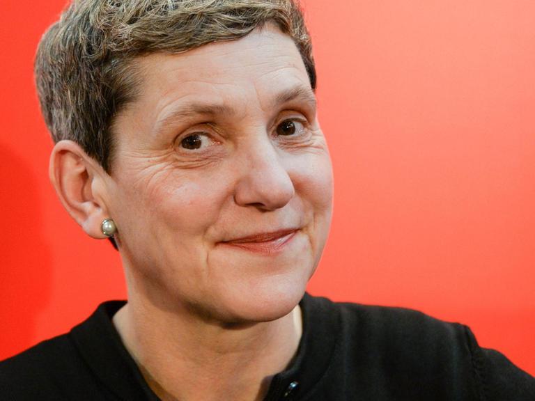 Die Autorin Felicitas Hoppe lächtelt vor einem roten Hintergrund seitlich in die Kamera