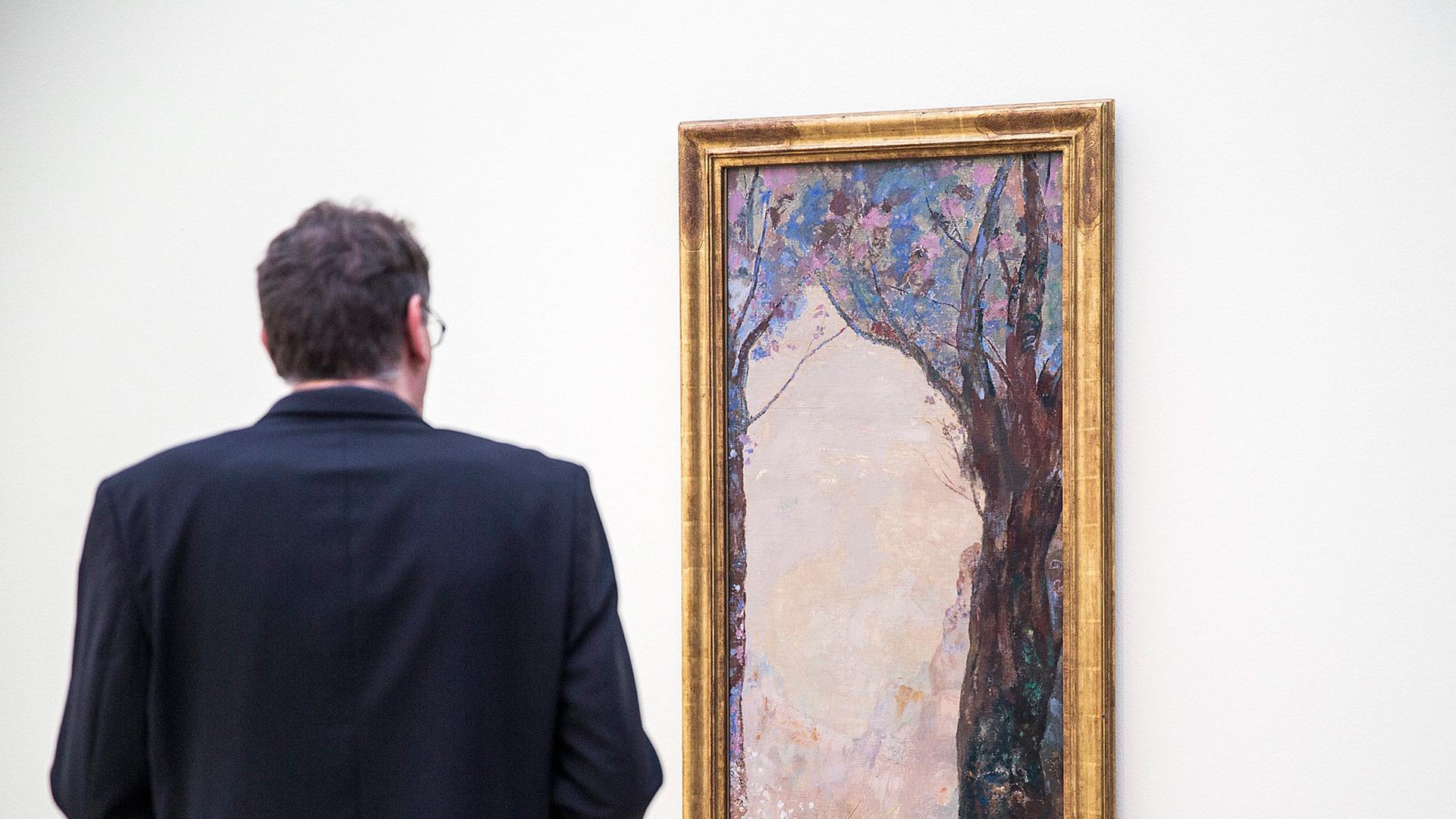 Ein Ausstellungsbesucher steht vor einem Werk von Odilon Redon. Ein Ausstellungsbesucher steht vor einem Werk von Odilon Redon.