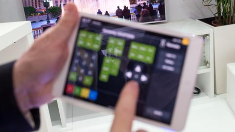 Ein Mitarbeiter des Zentralverbandes der deutschen Elektro- und Informationstechnischen Handwerke hält auf der Handwerksmesse IHM ein Tablet in einem E-Haus in den Händen.