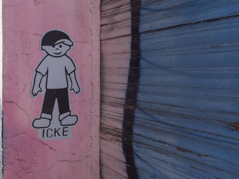 Auf einer Wand ist die stilisierte Figur eines Jungen geklebt. Darunter steht "Icke".