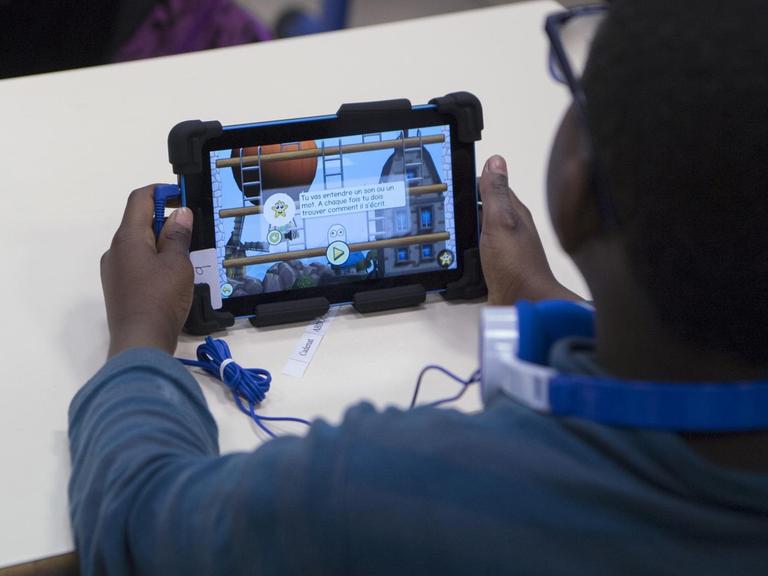 Ein Grundschüler in Marseille mit einem Lernprogramm auf einem Tablet