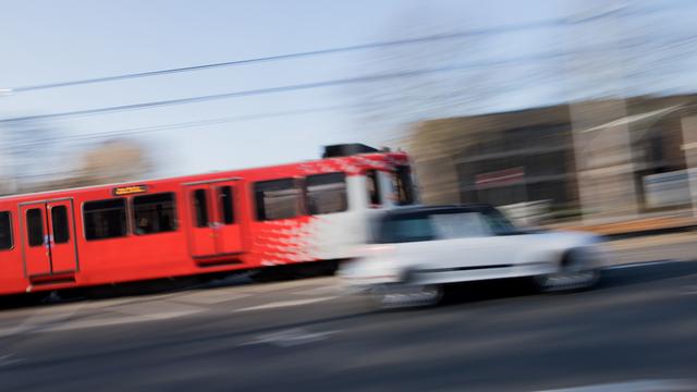 Eine Straßenbahn und ein Auto fahren durch das ehemalige Regierungsviertel in Bonn, Modellstadt für kostenlosen ÖPNV