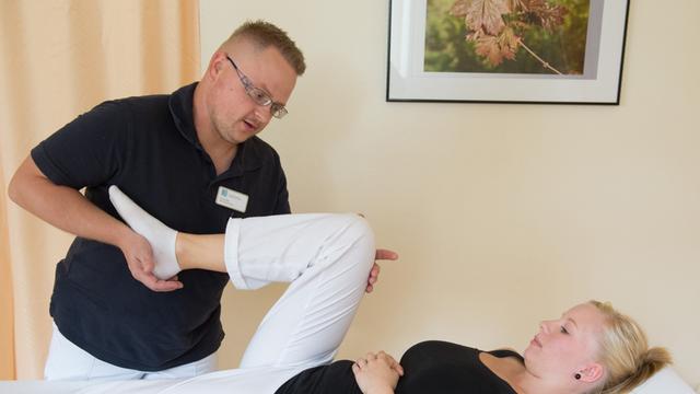 Ein Physiotherapeut behandelt Knieprobleme einer jungen Patientin.