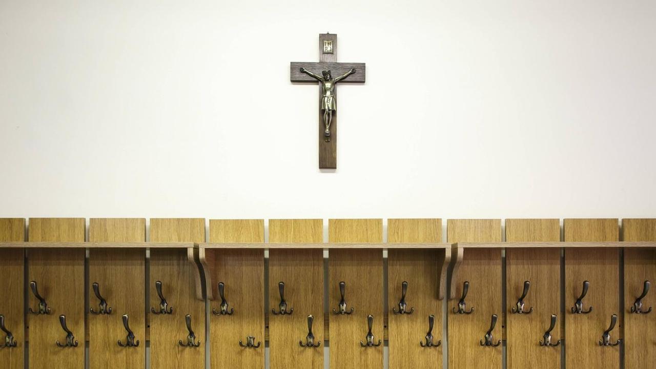 Ein Kruzifix hängt über einer Garderobe