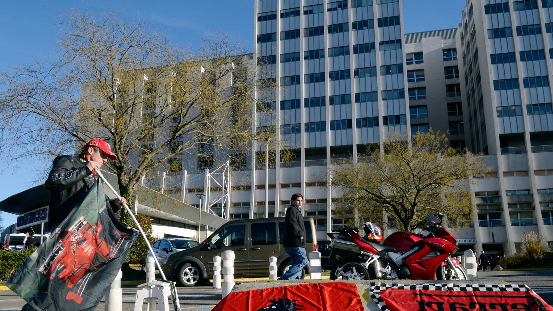 Ein Fan Michael Schumachers legt Ferrari-Fahnen vor der Uniklinik Grenoble in Frankreich aus, in der der verunglückte siebenmalige Formel-1-Weltmeister behandelt wird. Ein Fan Michael Schumachers legt Ferrari-Fahnen vor der Uniklinik Grenoble in Frankreich aus, in der der verunglückte siebenmalige Formel-1-Weltmeister behandelt wird.
