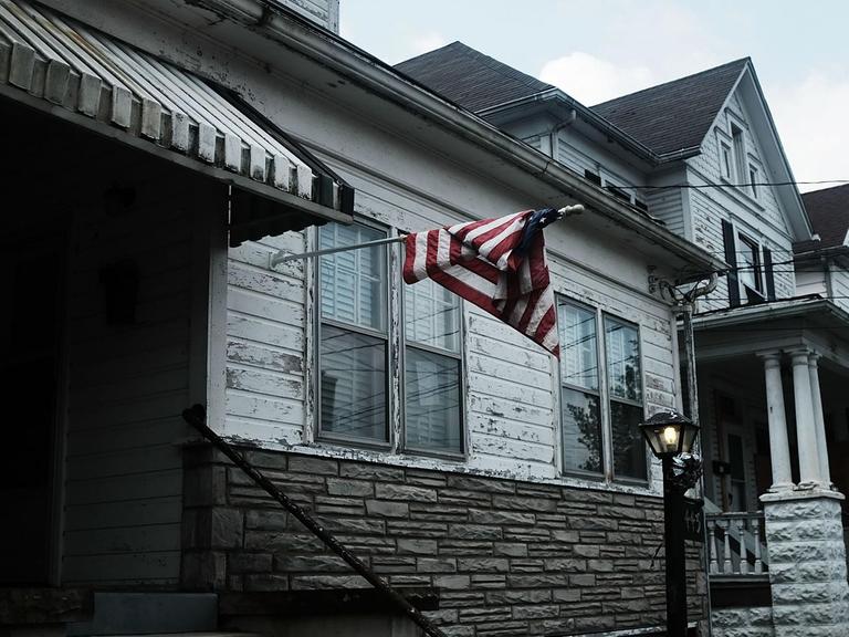 Eine amerikanische Flagge hängt einsam an einem Haus in Clarksburg, West Virginia. Die ganze Häuserzeile sieht arm und unrenoviert aus.