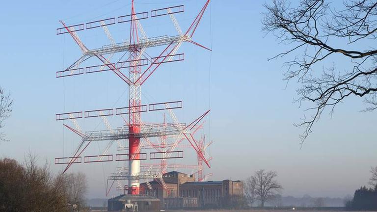 Großfunkstelle Nauen. Ein Funkmast steht auf einer Wiese, im Hintergrund ein Gebäude Großfunkstelle Nauen. Ein Funkmast steht auf einer Wiese, im Hintergrund ein Gebäude