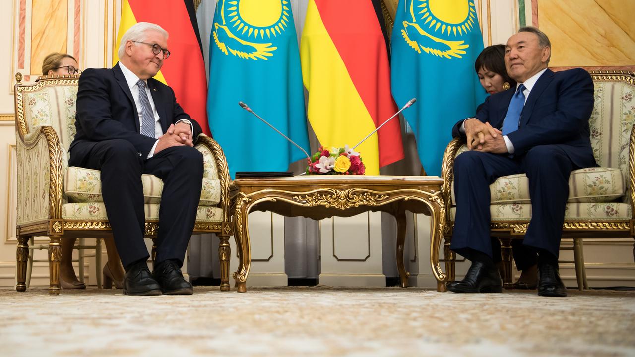 Bundespräsident Frank-Walter Steinmeier sitzt auf einem Sessel mit Goldschmuck neben dem kasachischen Präsidenten Nursultan Nasarbajew. Dahinter Fahnen von Deutschland und Kasachstan. Bundespräsident Frank-Walter Steinmeier sitzt auf einem Sessel mit Goldschmuck neben dem kasachischen Präsidenten Nursultan Nasarbajew. Dahinter Fahnen von Deutschland und Kasachstan.