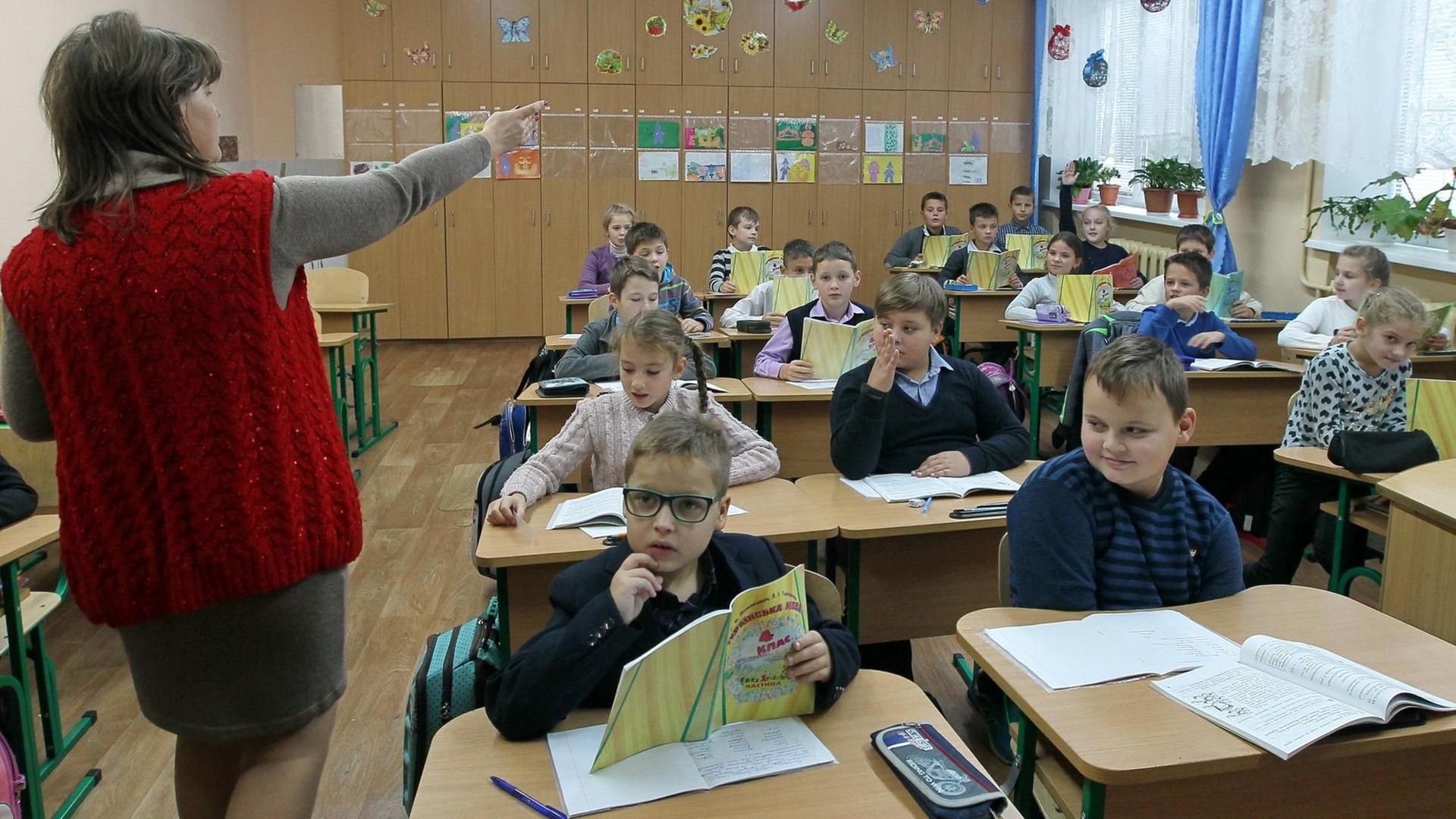 Eine Unterrichtsstunde in Ukrainisch an einer Grundschule in der Region Kiew, im Oktober 2017. Links im Bild die Lehrerin weist auf die Schüler.