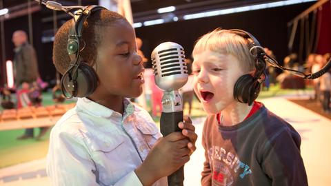 Der sechsjährige Darlington (links) und der gleichaltrige Marvin aus der Frankfurter Kita "Kantapfel" singen am 11.03.2014 in Frankfurt am Main (Hessen) auf der Musikmesse bei der jährlichen Mitmachaktion "music4kids" in ein Mikrofon.