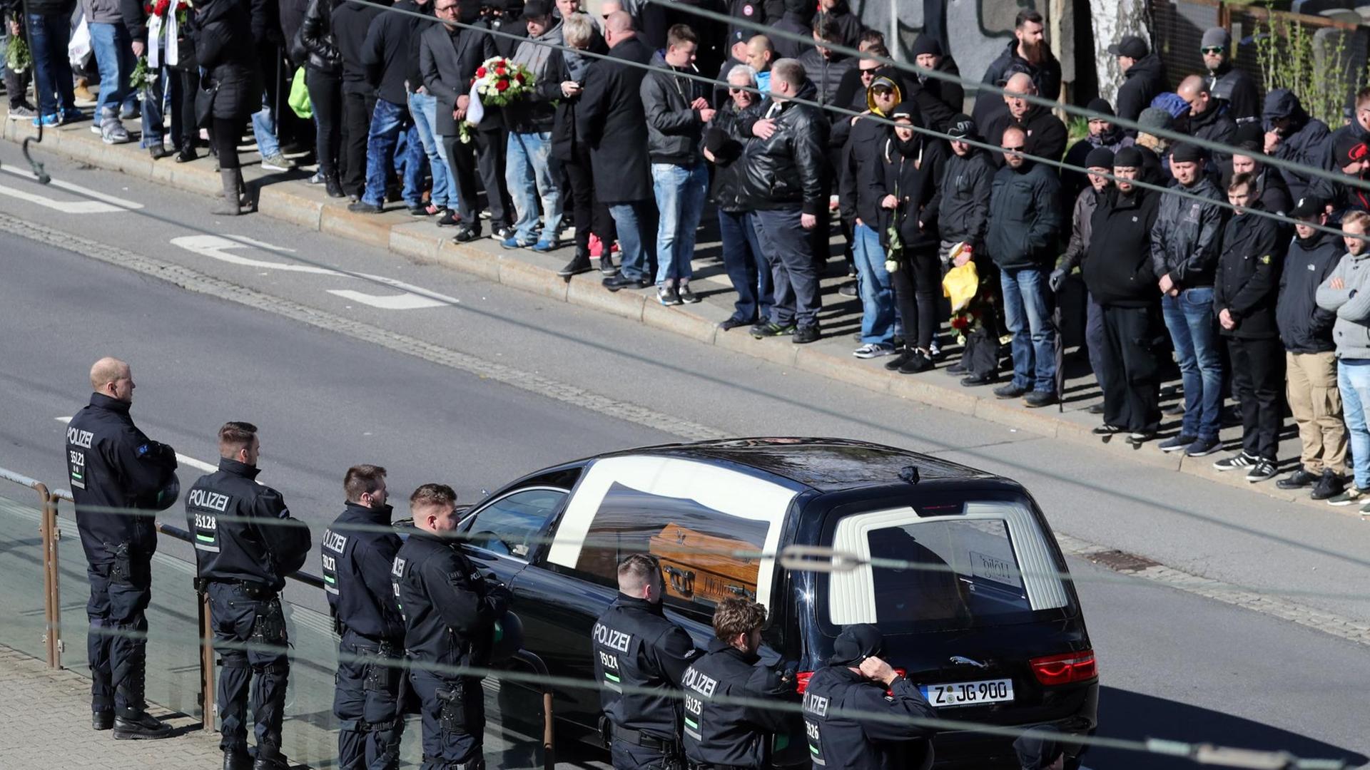 Teilnehmer eines Trauerzugs sehen zum Leichenwagen mit Sarg auf dem Weg zur Beerdigung des verstorbenen Rechtsextremisten in Chemnitz.
