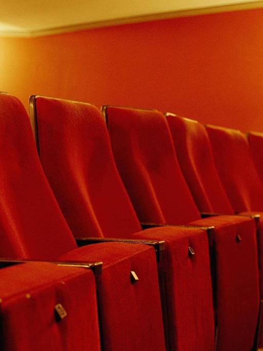 Ein leerer Kinosaal mit roten Sitzen.