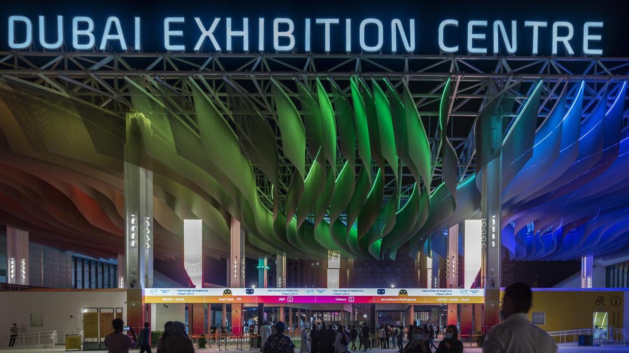 Eingang der Expo 2020 in Dubai bei Dunkelheit: In Neonlicht steht "Dubai Exhibition Center" über dem Eingang. Eingang der Expo 2020 in Dubai bei Dunkelheit: In Neonlicht steht "Dubai Exhibition Center" über dem Eingang.