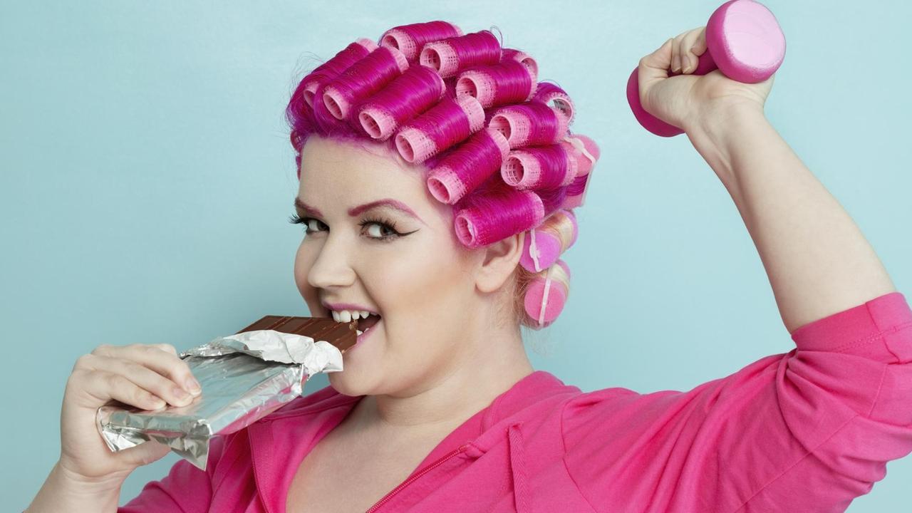 Fröhliche junge Frau genießt eine Tafel Schokolade.