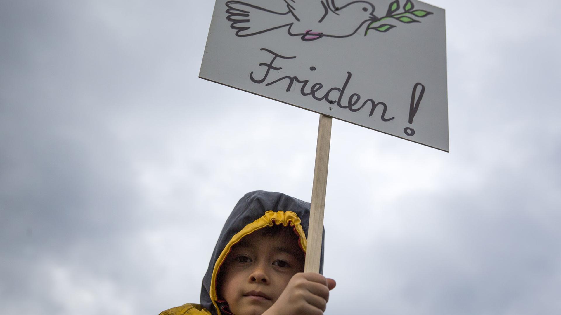 Ein Kind trägt am Potsdamer Platz in Berlin ein Plakat mit einer Friedenstaube Ein Kind trägt am Potsdamer Platz in Berlin ein Plakat mit einer Friedenstaube