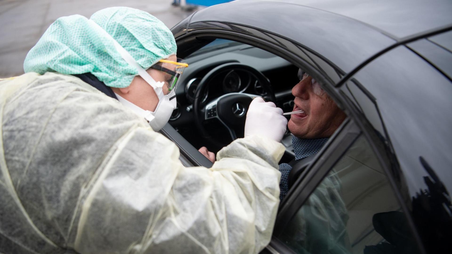 Eine Mitarbeiterin eines Krankenhauses nimmt während eines Pressetermins zum Start einer "Drive-In"-Teststation für den Coronavirus eine Probe durch ein Autofenster. Eine Mitarbeiterin eines Krankenhauses nimmt während eines Pressetermins zum Start einer "Drive-In"-Teststation für den Coronavirus eine Probe durch ein Autofenster.