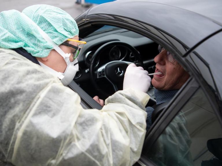 Eine Mitarbeiterin eines Krankenhauses nimmt während eines Pressetermins zum Start einer "Drive-In"-Teststation für den Coronavirus eine Probe durch ein Autofenster.