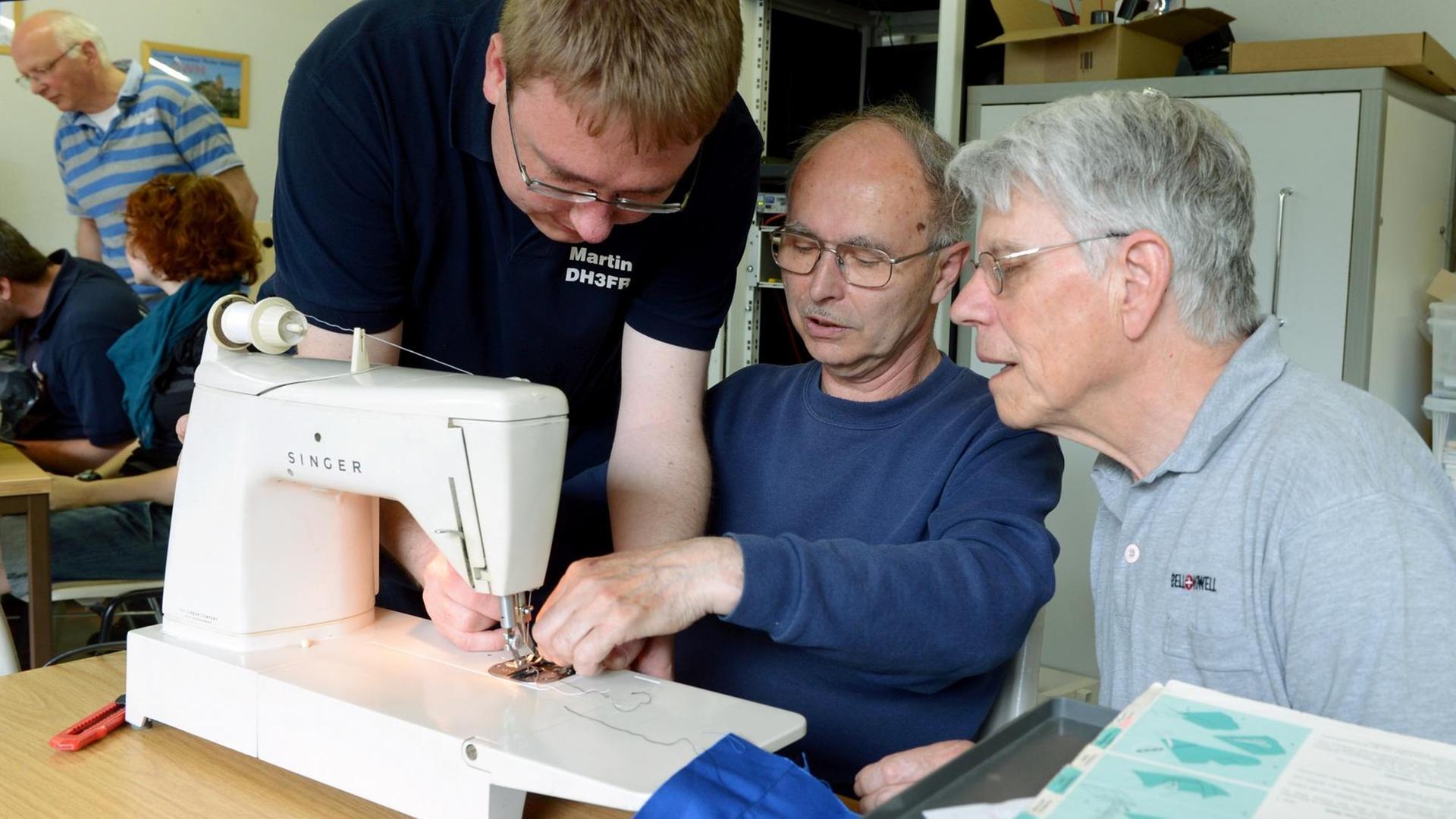 Der Diplom-Ingenieur und leidenschaftliche Bastler Martin Kramer (l) repariert im Repair-Café zusammen mit Johann Schütt (M) eine Nähmaschine von Wolfgang Rogoll. Der Diplom-Ingenieur und leidenschaftliche Bastler Martin Kramer (l) repariert im Repair-Café zusammen mit Johann Schütt (M) eine Nähmaschine von Wolfgang Rogoll.