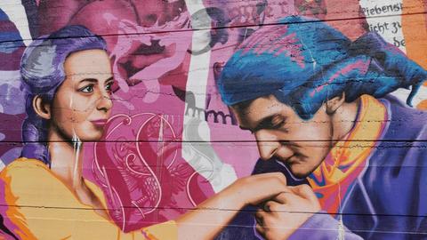 Christiane Spory steht vor einem Graffiti, das den jungen Goethe und Charltote Buff zeigt.