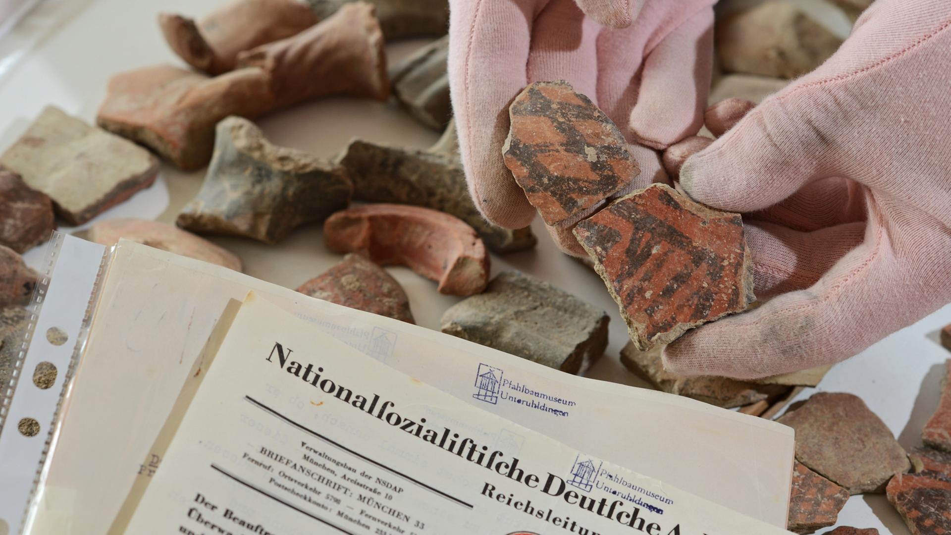 Ein wissenschaftlicher Mitarbeiter hält am 18.02.2013 im Pfahlbaumuseum in Unteruhldingen (Baden-Württemberg) eine rot-schwarz bemalte Keramik der griechischen Jungsteinzeit um 4.800 vor Christus neben einem Schreiben von Hitlers Chefideologen Alfred Rosenberg an Professor Hans Reinerth von der Reichsleitung in der Hand. Das Pfahlbaumuseum in Uhldingen am Bodensee will Griechenland rund 10 000 Tonscherben aus der Jungsteinzeit zurückgeben. Sie wurden 1941 unter Hitlers Chefideologen Alfred Rosenberg von deutschen Archäologen ausgegraben - damals mit der Genehmigung griechischer Behörden. Ein wissenschaftlicher Mitarbeiter hält am 18.02.2013 im Pfahlbaumuseum in Unteruhldingen (Baden-Württemberg) eine rot-schwarz bemalte Keramik der griechischen Jungsteinzeit um 4.800 vor Christus neben einem Schreiben von Hitlers Chefideologen Alfred Rosenberg an Professor Hans Reinerth von der Reichsleitung in der Hand. Das Pfahlbaumuseum in Uhldingen am Bodensee will Griechenland rund 10 000 Tonscherben aus der Jungsteinzeit zurückgeben. Sie wurden 1941 unter Hitlers Chefideologen Alfred Rosenberg von deutschen Archäologen ausgegraben - damals mit der Genehmigung griechischer Behörden.