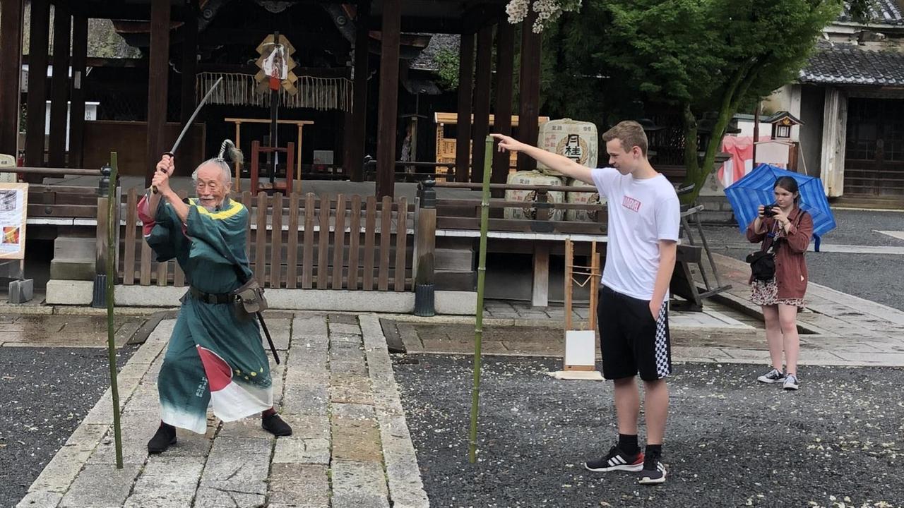 Der 90jährige Joe Okada führt Katana-Schwertkunst-Übungen aus - Besucher schauen zu Der 90jährige Joe Okada führt Katana-Schwertkunst-Übungen aus - Besucher schauen zu