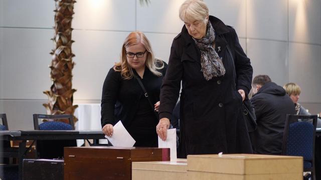 Zwei Frauen werfen in einem Wahllokal der isländischen Hauptstadt Reykjavik ihre Wahlzettel in die Urne.