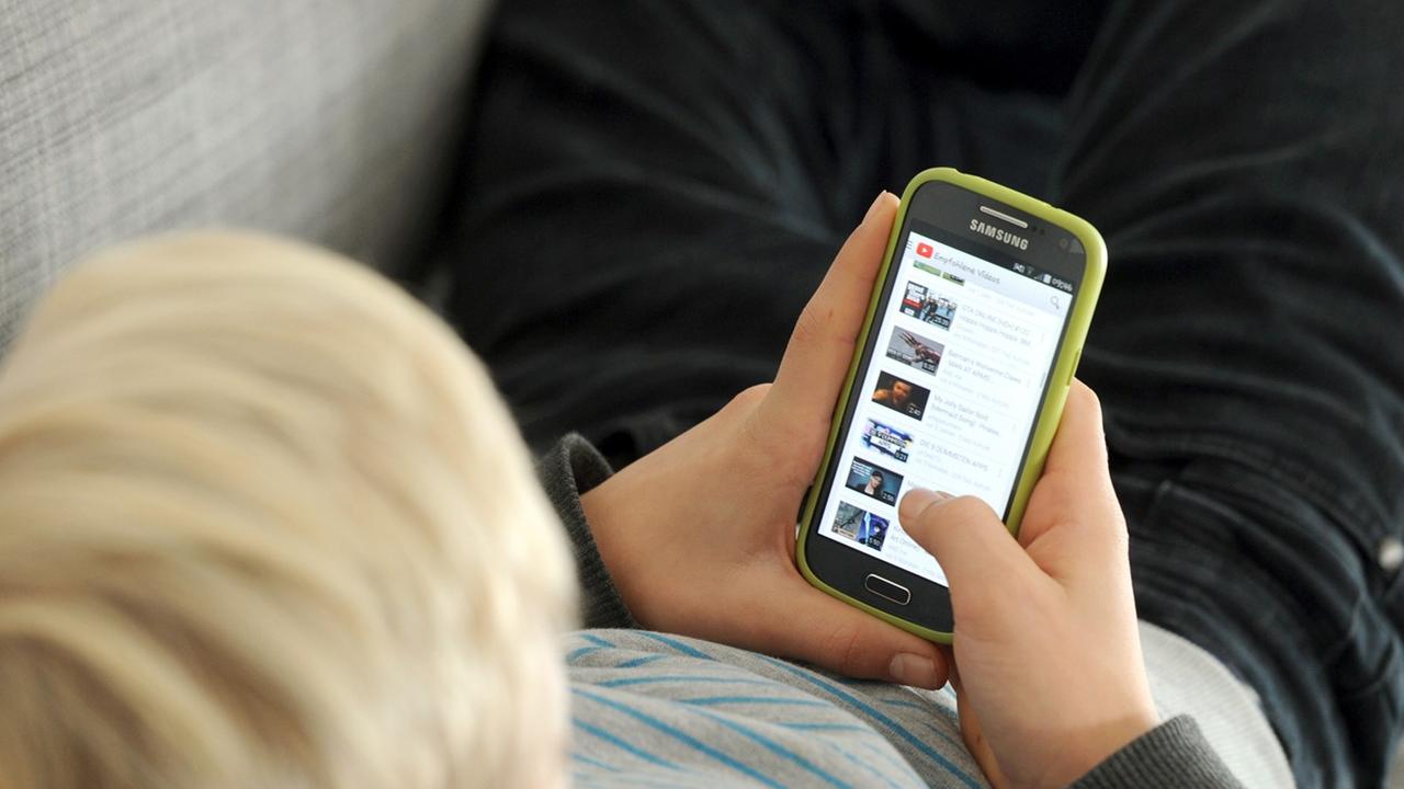 Ein Jugendlicher betrachtet Inhalte auf seinem Smartphone. Ein Jugendlicher betrachtet Inhalte auf seinem Smartphone.