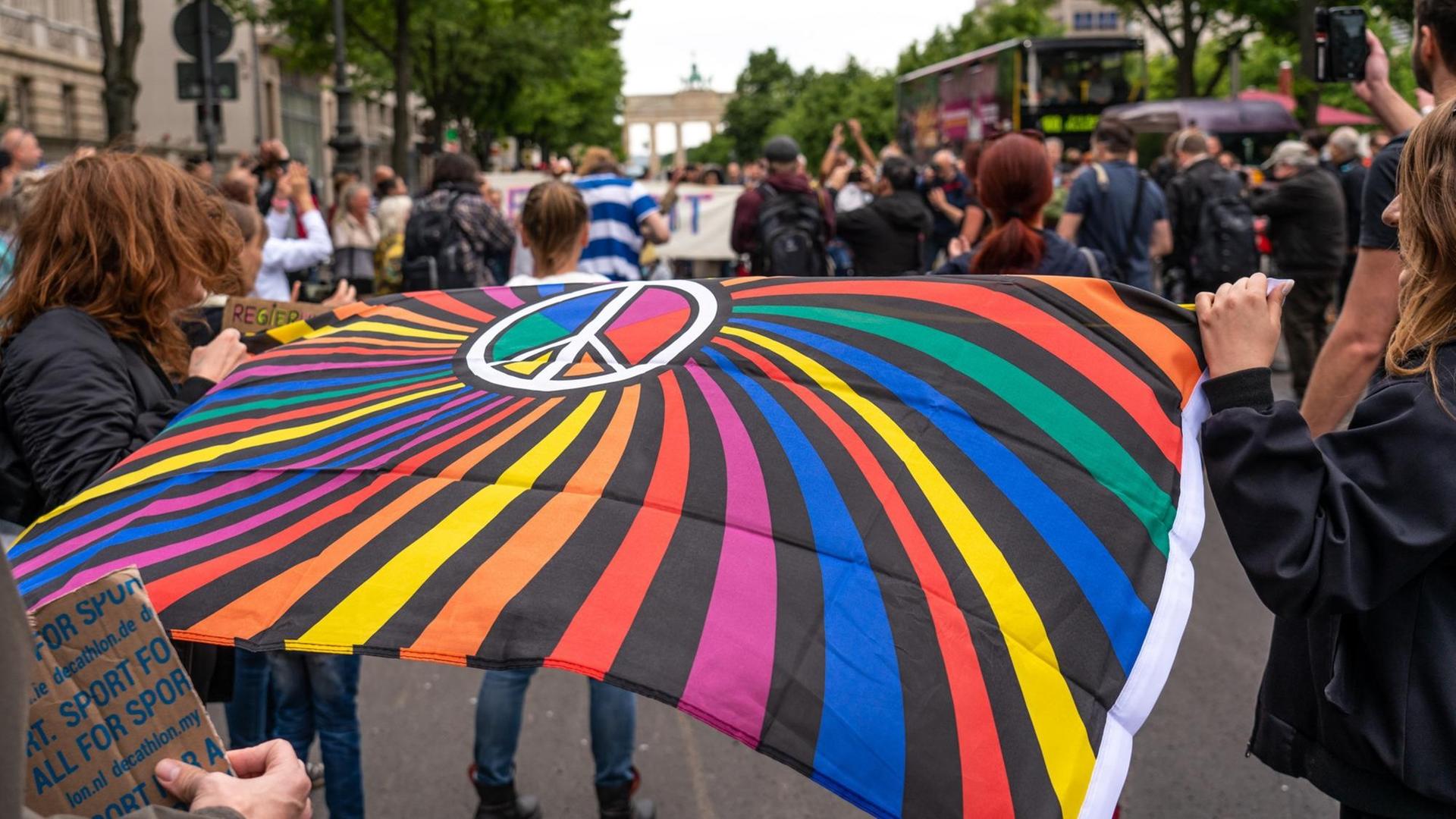 Impression von einer "Hygiene-Demo" in Berlin: Demonstranten halten eine bunte Flagge mit dem Peace-Zeichen. Impression von einer "Hygiene-Demo" in Berlin: Demonstranten halten eine bunte Flagge mit dem Peace-Zeichen.