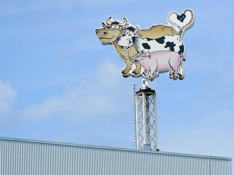 Auf dem Dach des Fleischverarbeiters Tönnies sind an einem Mast ein Bulle, eine Kuh und ein Schwein, deren Schwänze ein Herz bilden, als Werbefiguren abgebildet.
