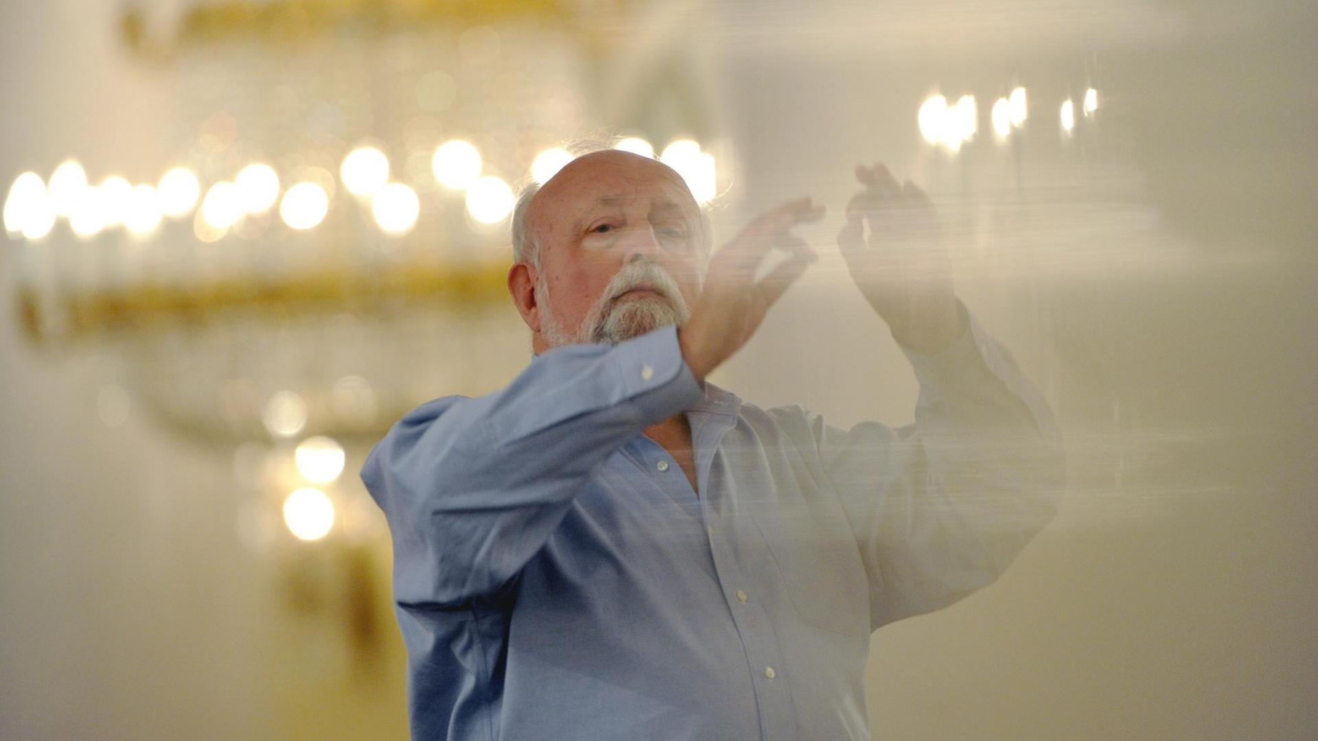 Krzysztof Penderecki steht in einem hell erleuchteten Saal und dirigiert. Krzysztof Penderecki steht in einem hell erleuchteten Saal und dirigiert.