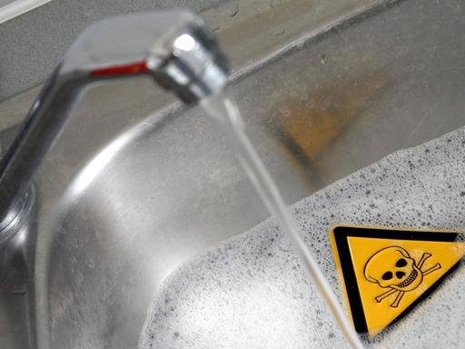 Symbolbild für Gefahren im Haushalt: Warnschild Achtung Gift in einer mit Wasser und Reinigungsmittel gefüllten Spüle in der Küche sowie Wasserhahn