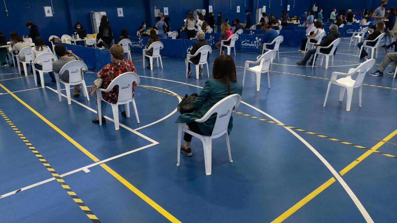In einer Turnhalle in Santiago de Chile, die zu einem Impfzentrum umfunktioniert wurde, warten im März 2021 Menschen in Plastikstühlen auf die Impfung mit Sinovac oder Pfizer. In einer Turnhalle in Santiago de Chile, die zu einem Impfzentrum umfunktioniert wurde, warten im März 2021 Menschen in Plastikstühlen auf die Impfung mit Sinovac oder Pfizer.