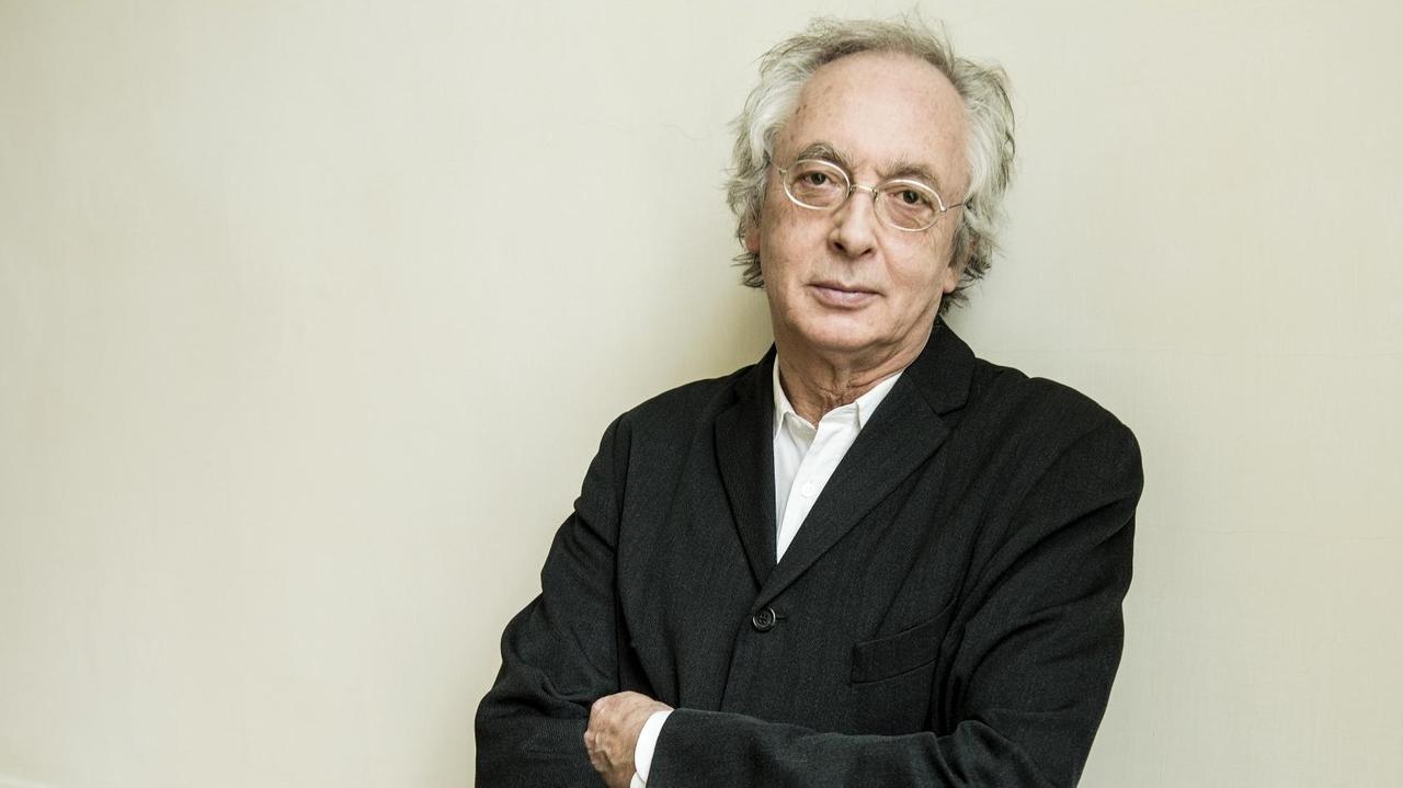 Philippe Herreweghe lehnt mit Brille an einer hellen Wand und schaut freundlich-ernst in die Kamera. Philippe Herreweghe lehnt mit Brille an einer hellen Wand und schaut freundlich-ernst in die Kamera.