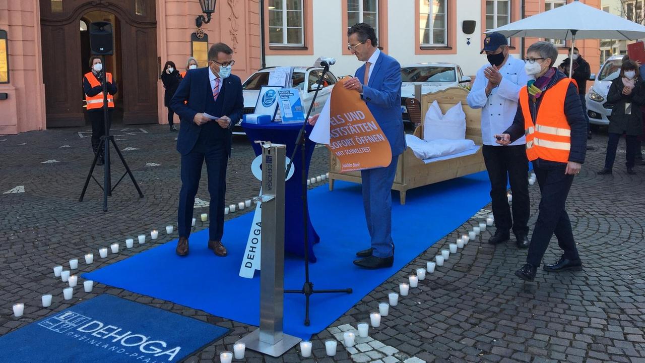Vor simulierter Hotel-Kulisse mit Bett und Teppich: Joachim Streit, Spitzenkandidat der Freien Wähler in Rheinland-Pfalz, entrollt ein Plakat mit seiner Wahlkampf-Forderung: „Hotels und Gaststätten sofort öffnen – mit Schnelltest“. Vor simulierter Hotel-Kulisse mit Bett und Teppich: Joachim Streit, Spitzenkandidat der Freien Wähler in Rheinland-Pfalz, entrollt ein Plakat mit seiner Wahlkampf-Forderung: „Hotels und Gaststätten sofort öffnen – mit Schnelltest“.
