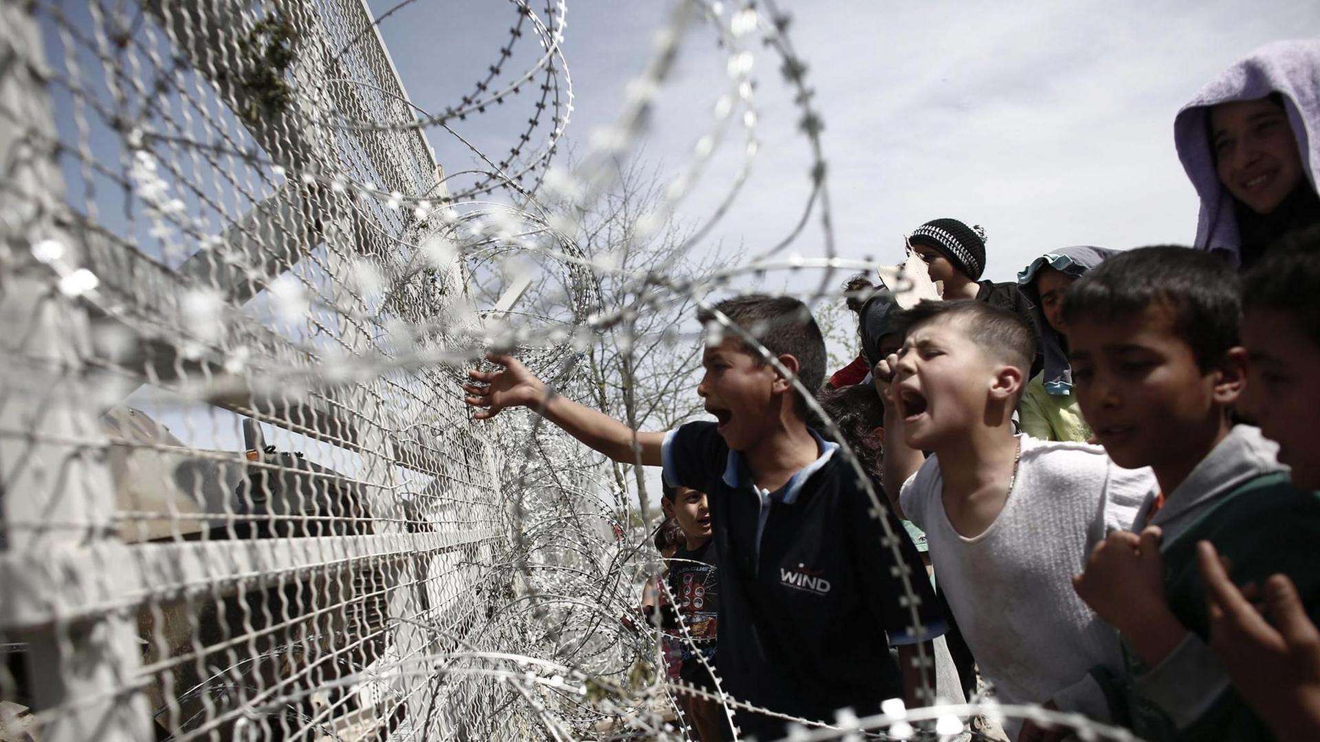Flüchtlingskinder an einem mit Stacheldraht ausgestatteten Zaun an der griechisch-mazedonischen Grenze im Lager Idomeni. Flüchtlingskinder an einem mit Stacheldraht ausgestatteten Zaun an der griechisch-mazedonischen Grenze im Lager Idomeni.