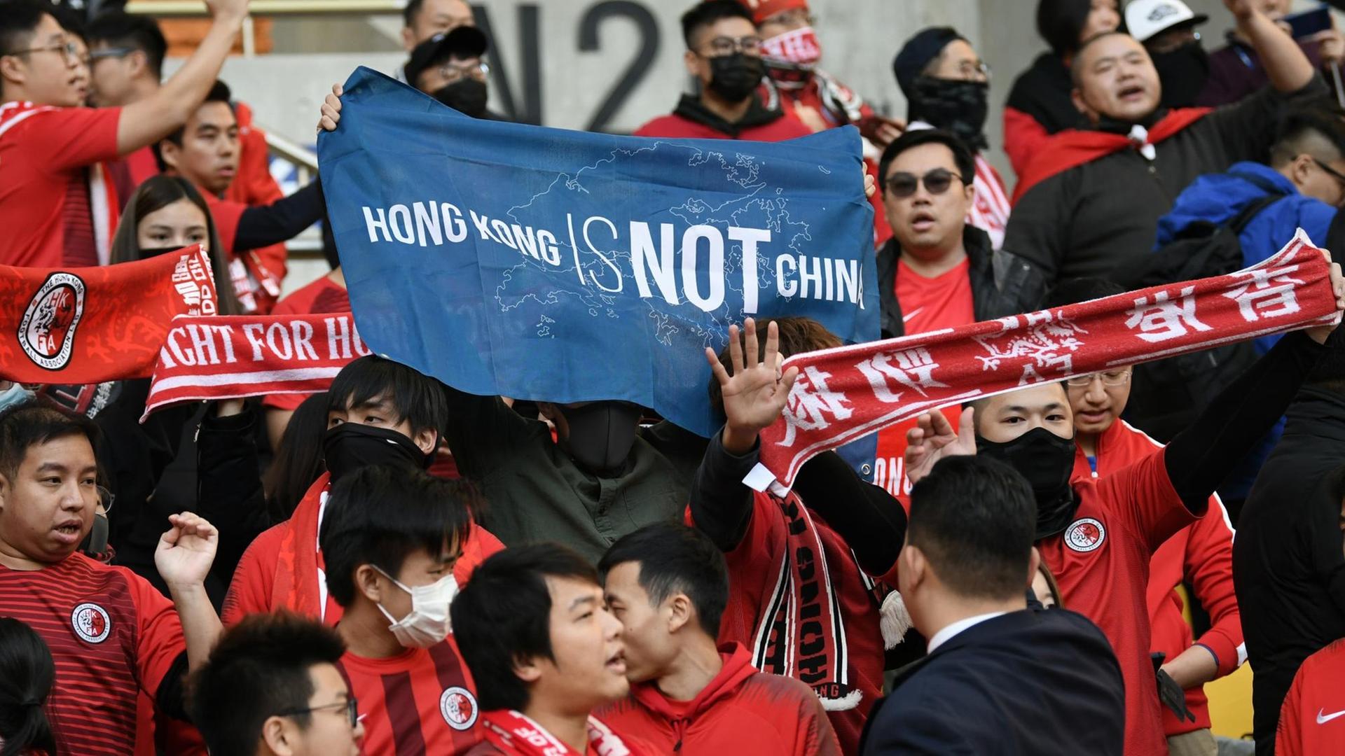 Fans von Hongkong halten ein Banner mit der Aufschrift "Hong Kong ist nicht China" während des Spiels zwischen Hongkong und China bei Ostasiatischen Meisterschaft in Südkorea im Dezember 2019. Fans von Hongkong halten ein Banner mit der Aufschrift "Hong Kong ist nicht China" während des Spiels zwischen Hongkong und China bei Ostasiatischen Meisterschaft in Südkorea im Dezember 2019.