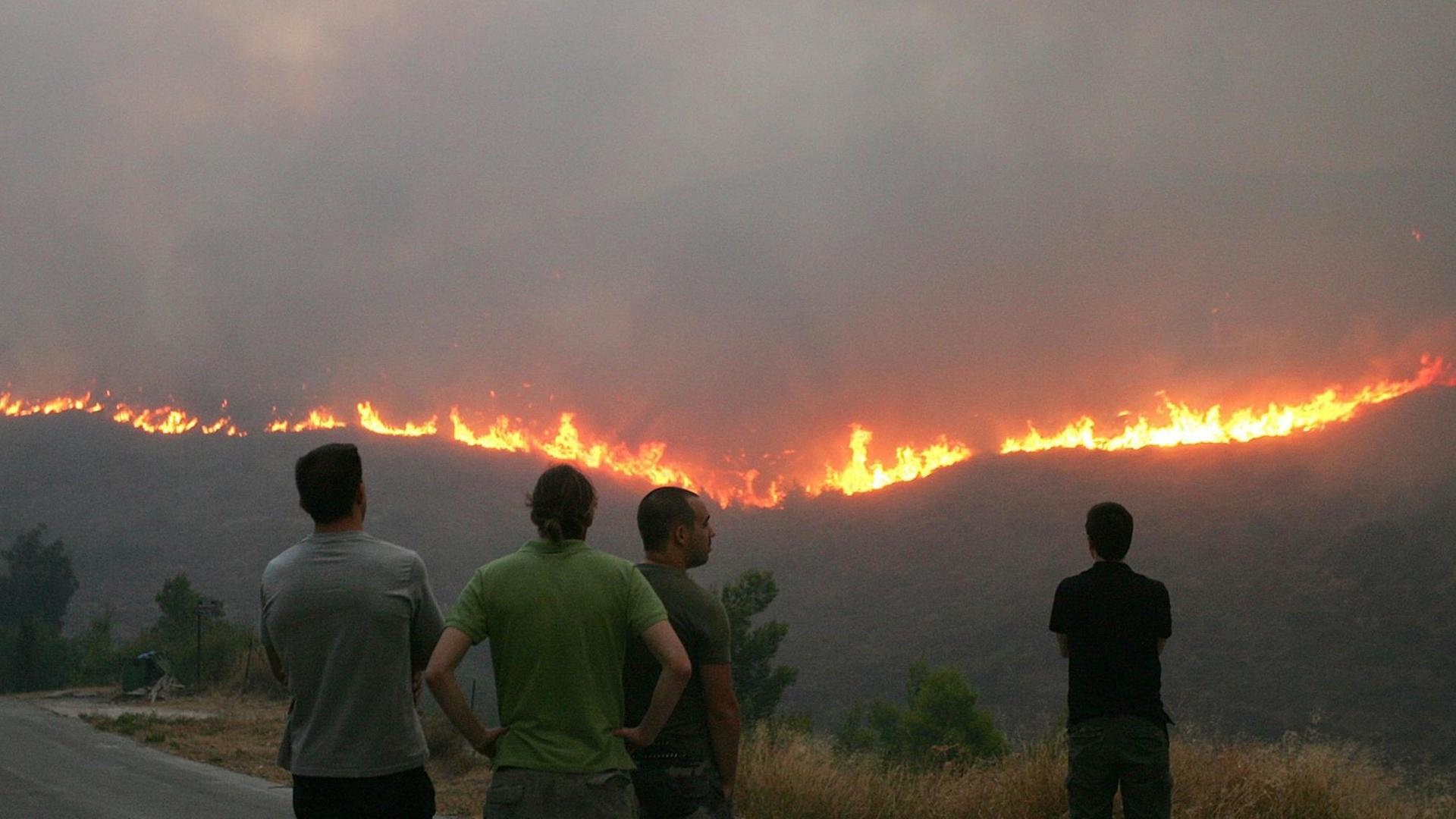 Anwohner betrachten aus der Ferne den sich ausbreitenden Waldbrand bei Athen.