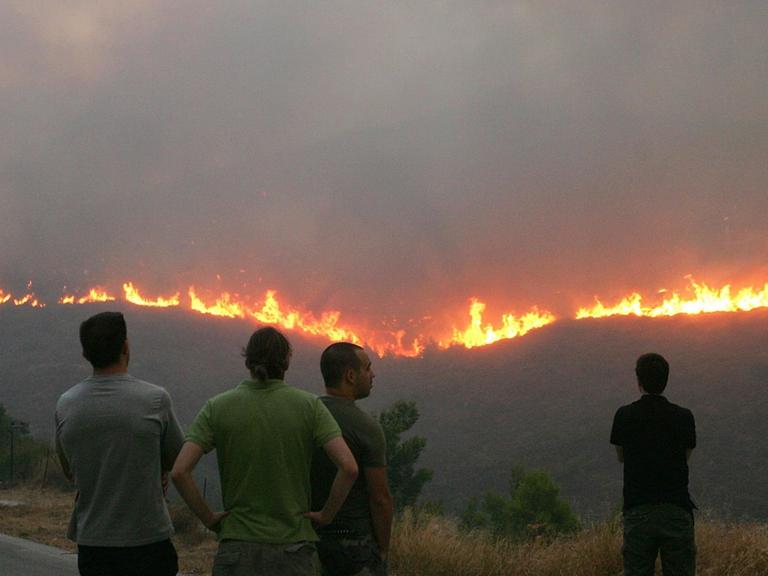 Anwohner betrachten aus der Ferne den sich ausbreitenden Waldbrand bei Athen.