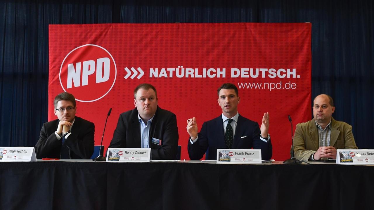 Man sieht von links nach rechts die NPD-Parteifunktionäre Peter Richter, Ronny Zasowk, den Parteivorsitzenden Frank Franz und Klaus Beier an einem Tisch vor einer roten Fahne. Man sieht von links nach rechts die NPD-Parteifunktionäre Peter Richter, Ronny Zasowk, den Parteivorsitzenden Frank Franz und Klaus Beier an einem Tisch vor einer roten Fahne.