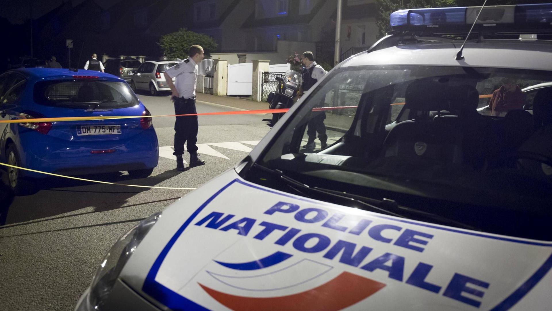 Ein Polizeiwagen und mehrere Beamte stehen auf einer Straße in Magnanville. Ein Polizeiwagen und mehrere Beamte stehen auf einer Straße in Magnanville.