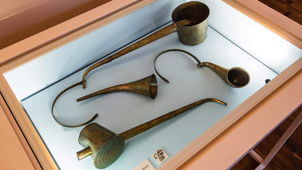 In einer Vitrine liegen vier verschieden gebogene Hörrohre mit unterschiedlichen Schallbechern. In einer Vitrine liegen vier verschieden gebogene Hörrohre mit unterschiedlichen Schallbechern.