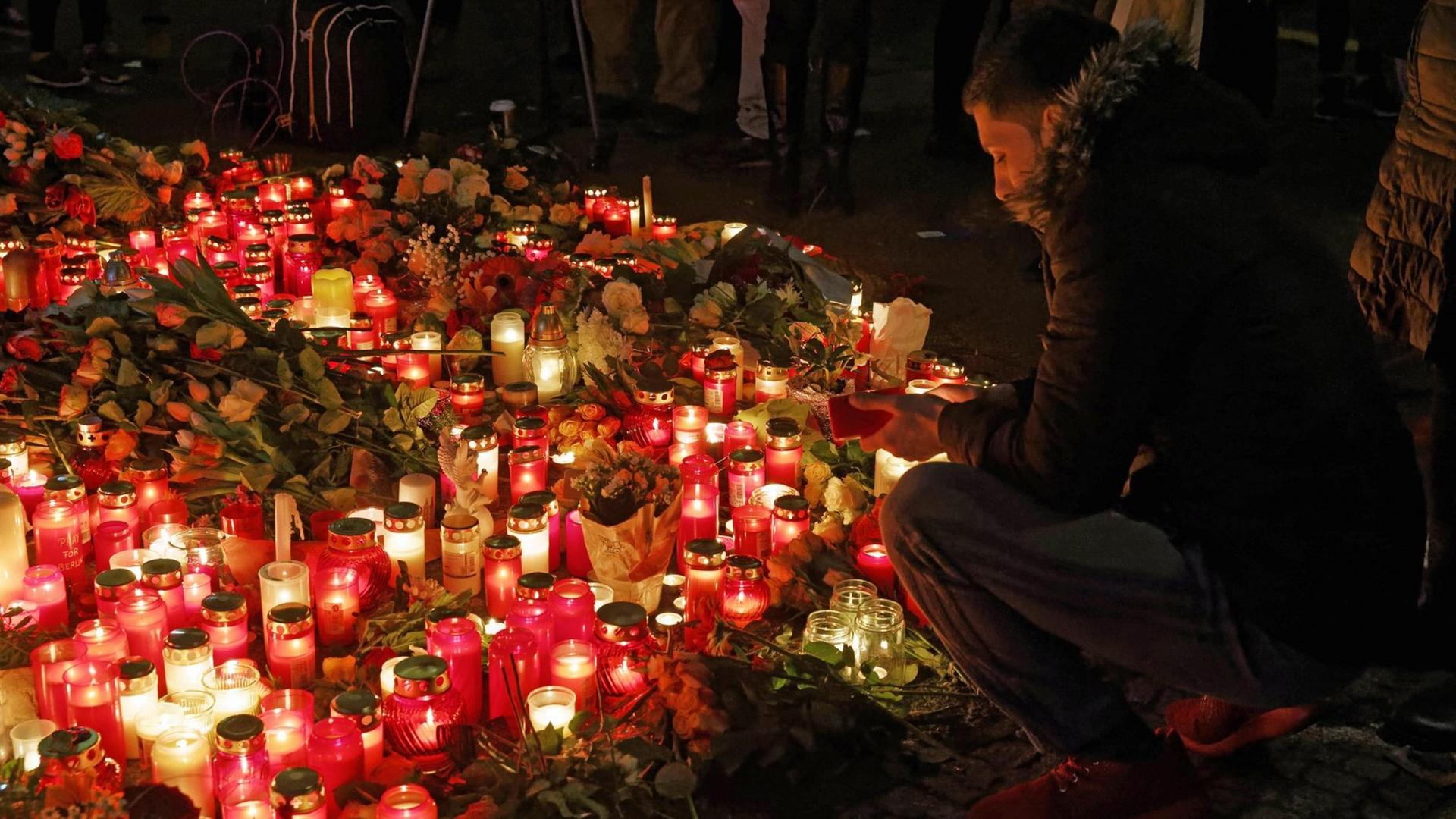 Ein Mann hockt vor einer erleuchteten Fläche aus Kerzen und Blumen am Breitscheidplatz Ein Mann hockt vor einer erleuchteten Fläche aus Kerzen und Blumen am Breitscheidplatz