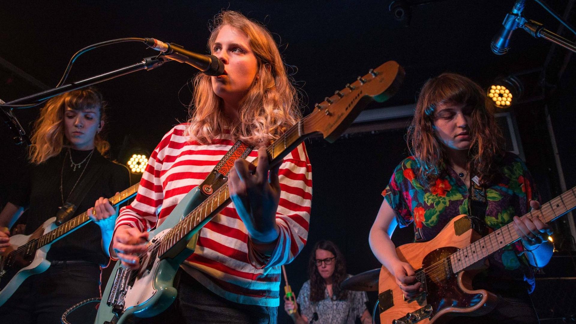 Die Musikerin Marika Hackman steht mit ihrer Gitarre auf der Bühne und singt. Sie wird von zwei weiteren Musikerinnen unterstützt. Die Musikerin Marika Hackman steht mit ihrer Gitarre auf der Bühne und singt. Sie wird von zwei weiteren Musikerinnen unterstützt.