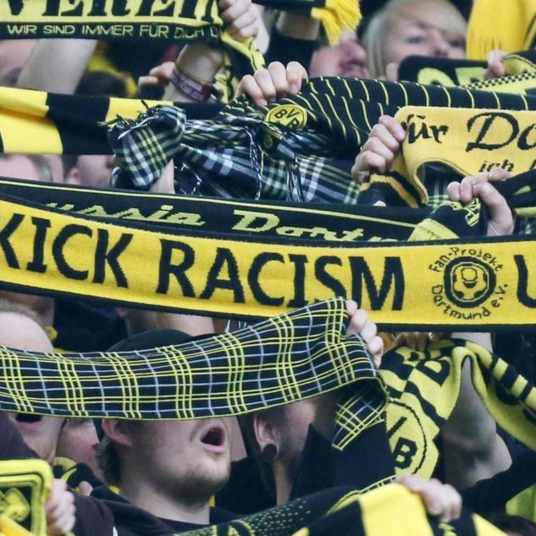 Ein Dortmund-Fan hält einen Anti-Rassismus-Schal im Fan-Block von Borussia Dortmund Borussia Dortmund hoch.