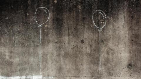 Auf eine Betonwand sind mit Kreide zwei Luftballons gemalt