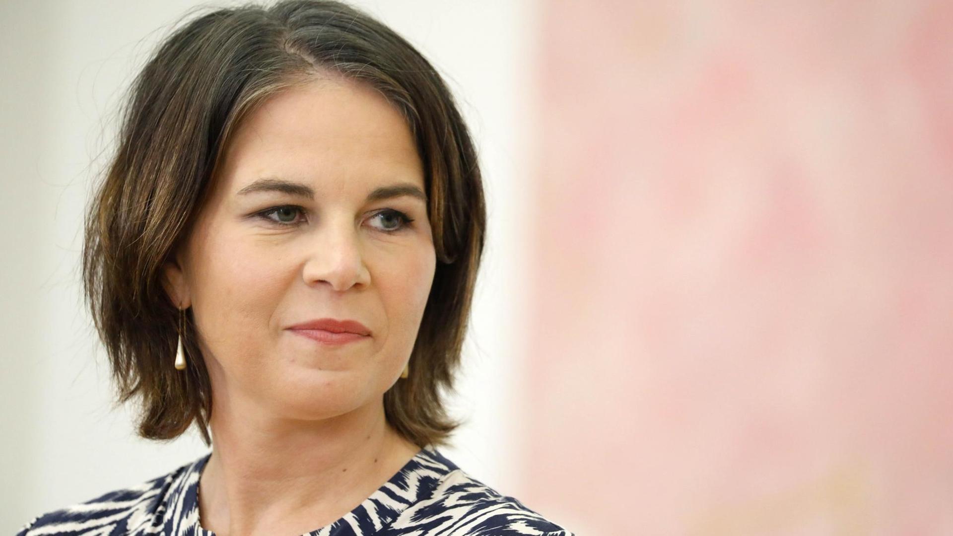 Außenministerin Annalena Baerbock steht vor einer rosa-weißen Wand. Außenministerin Annalena Baerbock steht vor einer rosa-weißen Wand.