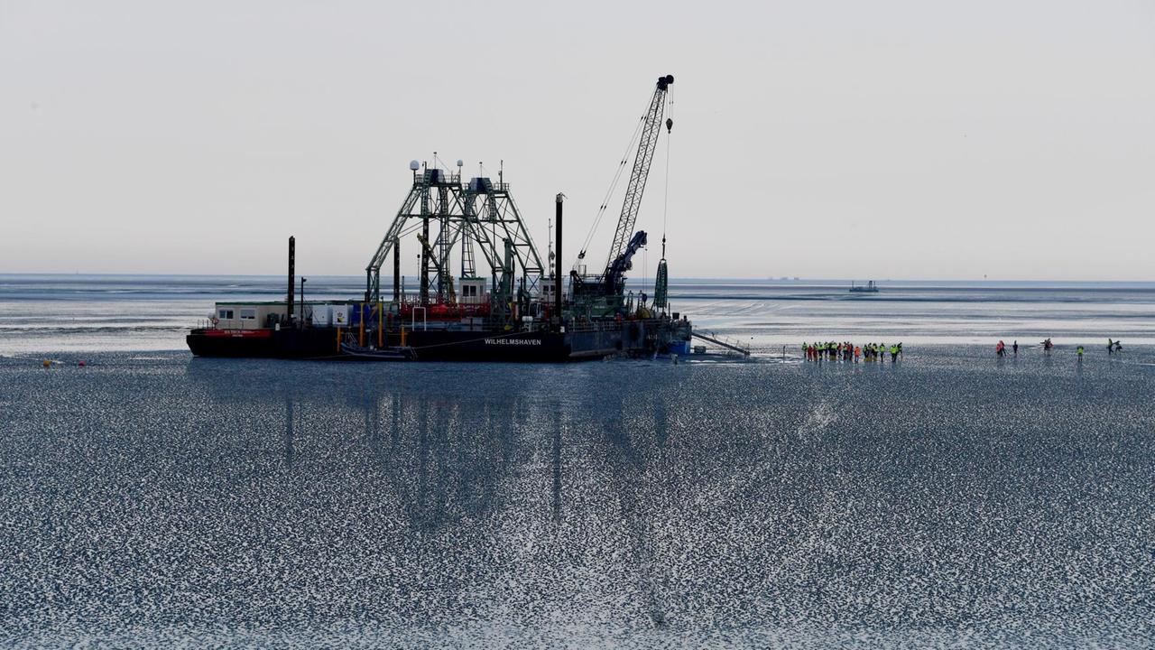 Das Endstück eines Seekabels wird von dem Kabelverlegeschiff "Boka Connector" im Watt unter dem Deich hindurch an Land gezogen. Das Endstück eines Seekabels wird von dem Kabelverlegeschiff "Boka Connector" im Watt unter dem Deich hindurch an Land gezogen.