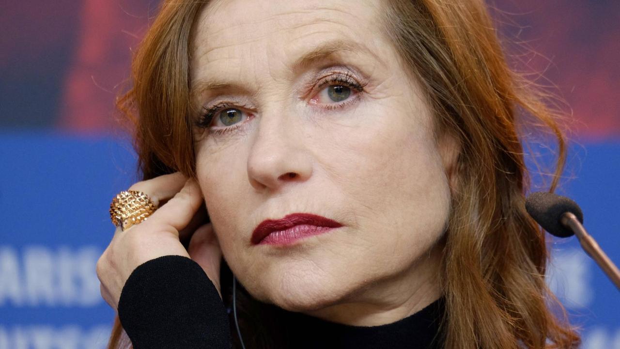 Isabelle Huppert blickt in einer Großaufnahme nachdenklich in die Kamera, zu sehen ist ein großer goldener Ring an ihrer Hand. Isabelle Huppert blickt in einer Großaufnahme nachdenklich in die Kamera, zu sehen ist ein großer goldener Ring an ihrer Hand.