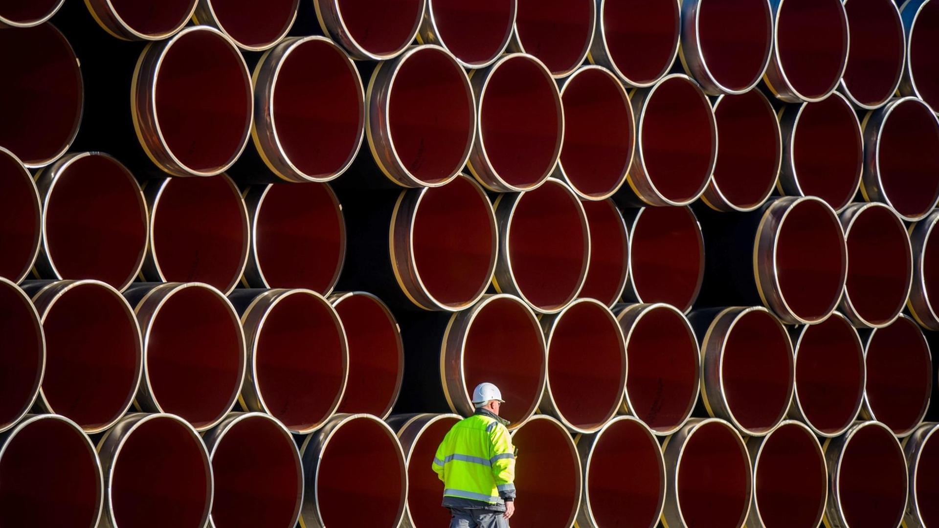 Ein Mann in Warnweste geht an den tonnenschweren Rohren für die zukünftige Ostsee-Erdgastrasse Nord Stream 2 auf einem Lagerplatz im Hafen von Sassnitz-Mukran vorbei.(2016) Ein Mann in Warnweste geht an den tonnenschweren Rohren für die zukünftige Ostsee-Erdgastrasse Nord Stream 2 auf einem Lagerplatz im Hafen von Sassnitz-Mukran vorbei.(2016)
